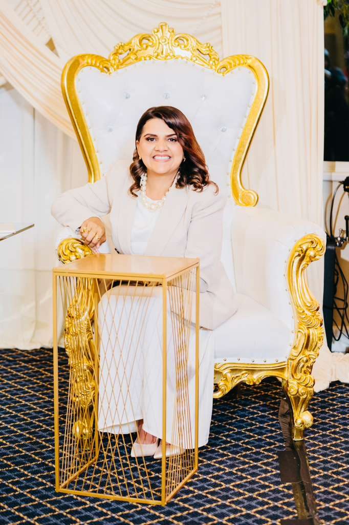 Denise Sampaio sentada em poltrona dourada